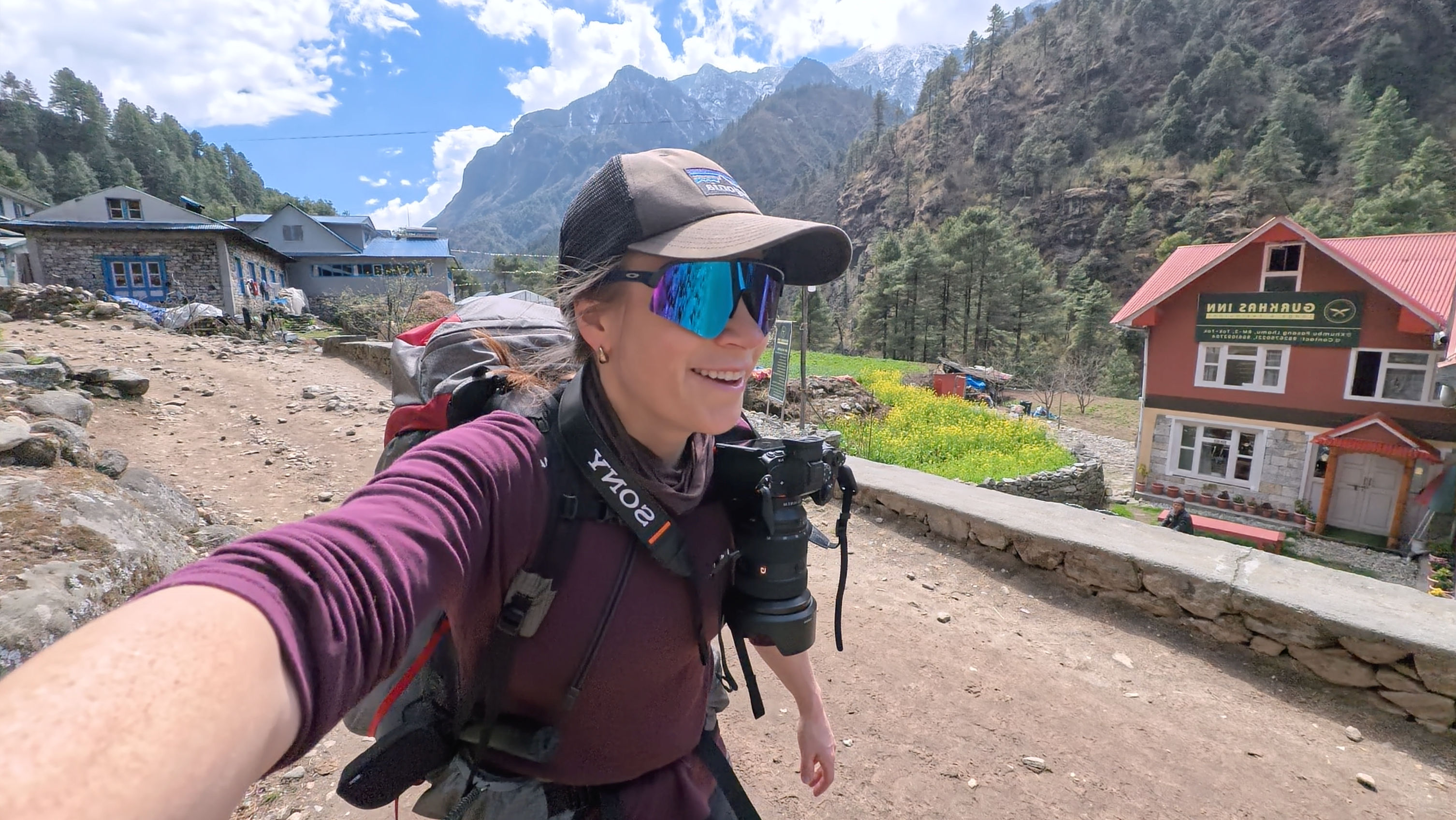 Person taking a selfie in a mountain village with houses and mountains in the background